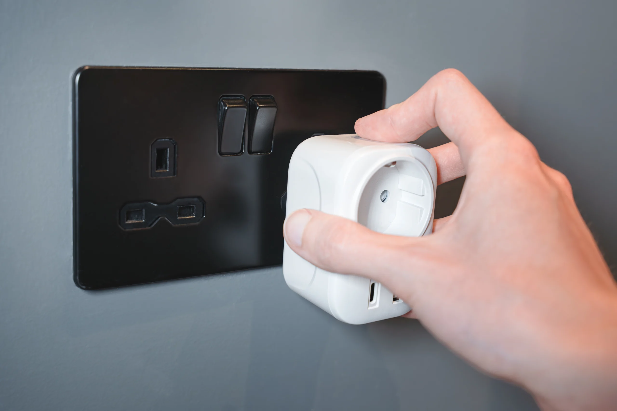 hand plugging smart plug into british power socket — best smart plugs 2026