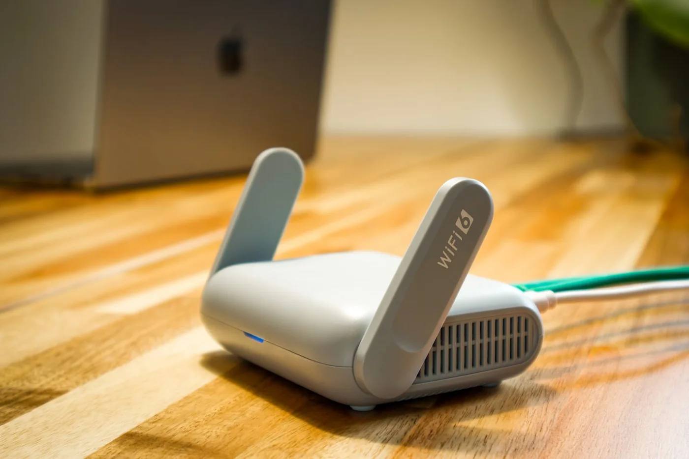 Wireless router on a wooden desk with Ethernet and power cables attached