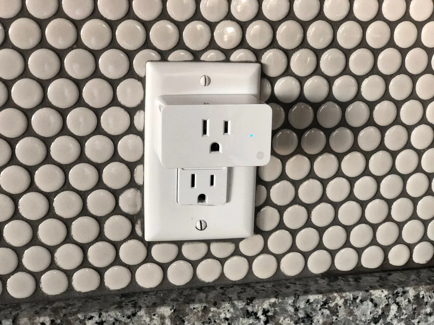 White plug-in smart socket installed on a tiled wall; illustrative model, not the products ranked below