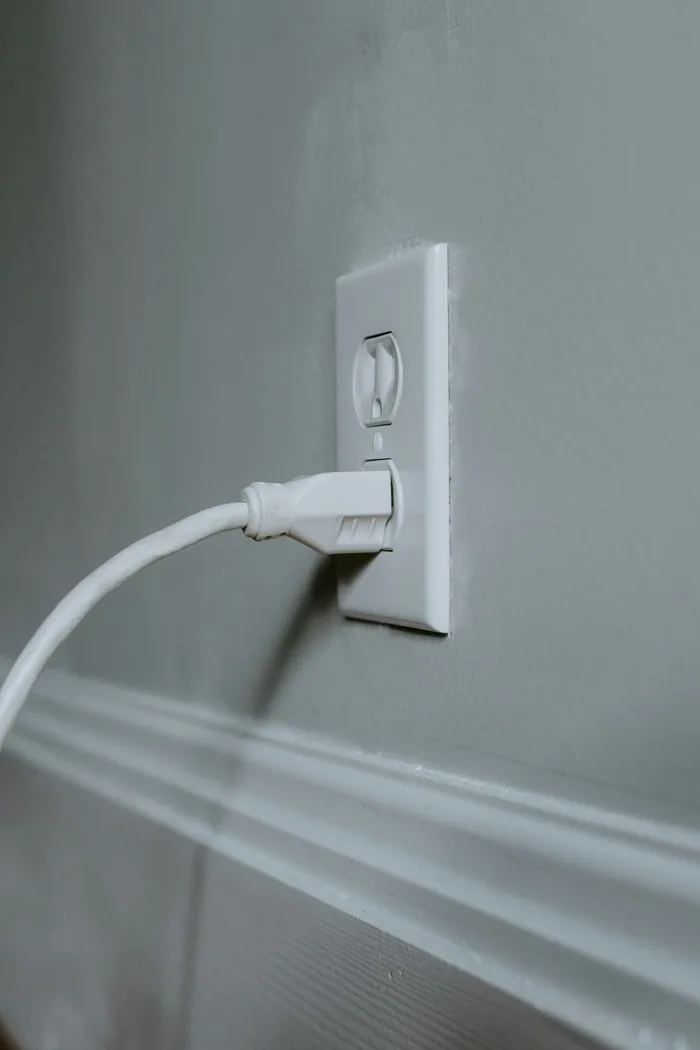 A white plug connected to a wall outlet; illustrative of ordinary outlet use
