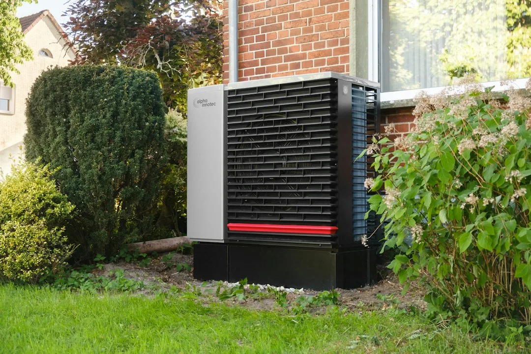 Outdoor residential heat pump unit beside a home, illustrating heat-pump heating and thermostat control